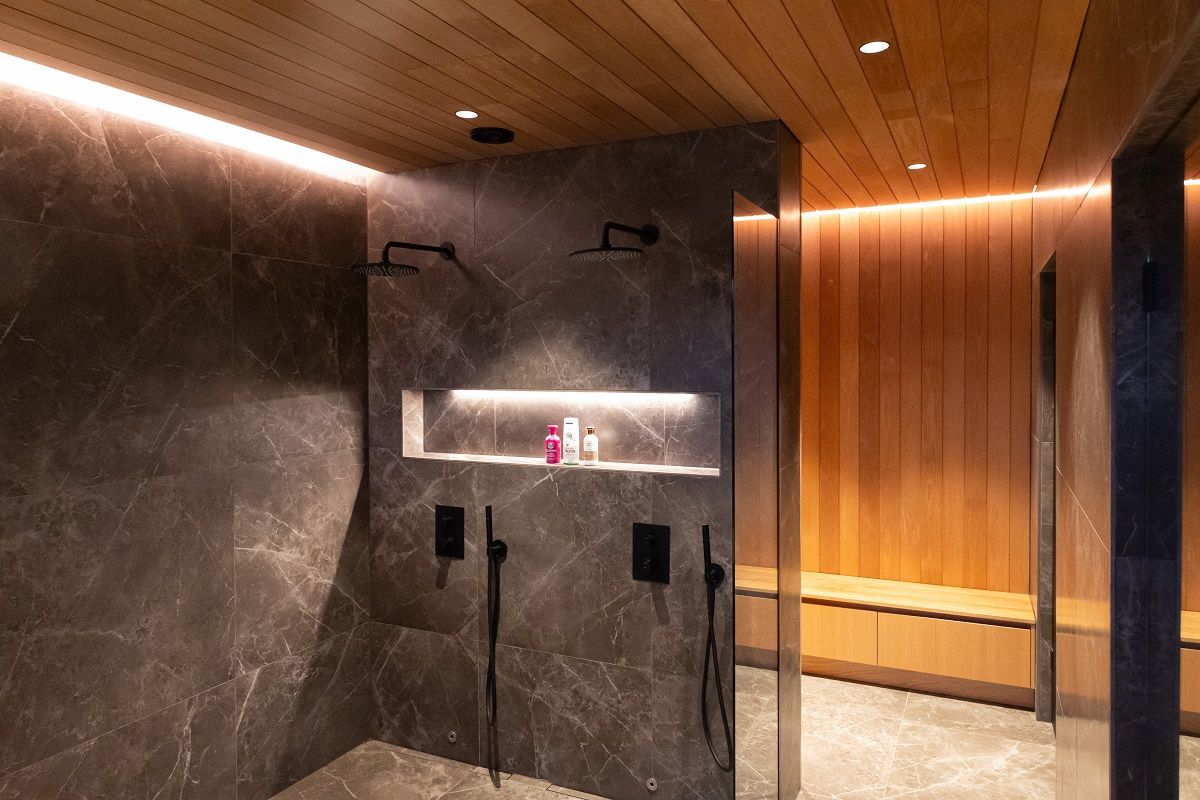 Bathroom and dressing room lighting with flush-mounted spotlights and indirect LED strip lighting along the ceiling. In addition, the shampoo shelf is illuminated by an LED strip in a compact aluminium profile.